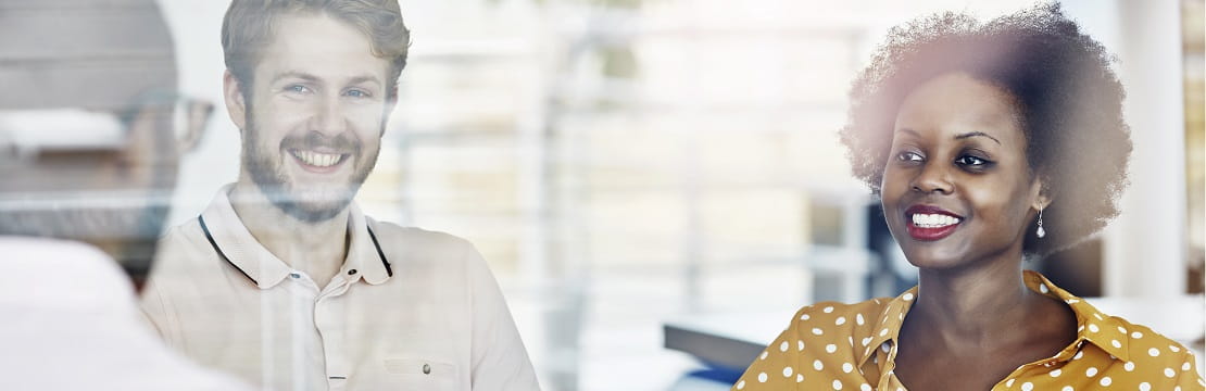Three people in business casual attire have a conversation in a glass-walled office.